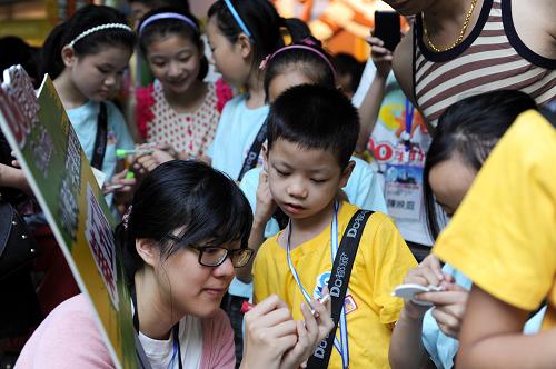 7月10日,參加夏令營的“小候鳥”在一位志愿者的幫助下書寫自己的暑期愿望。新華社記者 鞠煥宗 攝