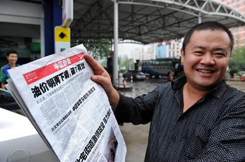 7月10日,蔣先生在青島東海路加油站翻看關(guān)于汽油降價(jià)的新聞。新華社記者 李紫恒 攝