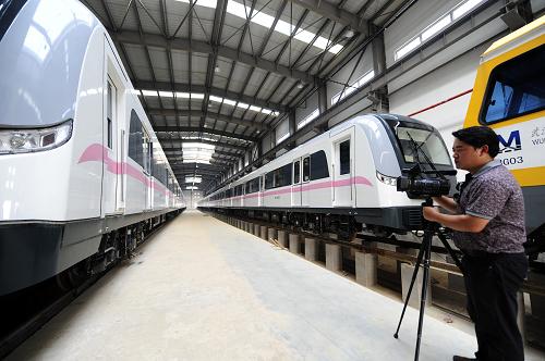 7月14日,一位記者在武漢地鐵2號線常青車輛段拍攝??吭谲噹靸?nèi)的地鐵列車。常青車輛段具備四大功能:車輛清洗、日常檢修、車輛大架修及停車和試車,可停泊32列車,是武漢首條地鐵的“車輛大本營”。武漢地鐵2號線是武漢的首條地鐵,也是我國第一條穿越長江的地鐵,起于漢口常青花園,終點為武昌魯巷,將成為武漢的“黃金交通走廊”。這條地鐵2006年8月開建,預(yù)計2012年年底竣工通車。新華社記者 郝同前 攝