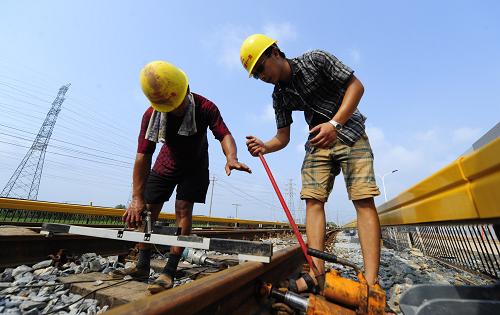 7月14日,中鐵十一局的施工人員在武漢地鐵2號線常青車輛段調(diào)整試車線的軌距。常青車輛段具備四大功能:車輛清洗、日常檢修、車輛大架修及停車和試車,可停泊32列車,是武漢首條地鐵的“車輛大本營”。新華社記者 郝同前 攝