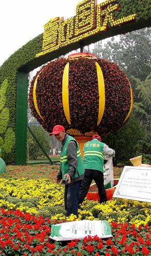 9月26日,濟(jì)南園林工人在舜耕路布置大型植物立體造型。新華社記者 徐速繪 攝