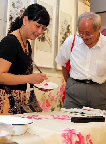 9月28日,來自洛陽市平樂村畫師王萍(左)在展覽現(xiàn)場(chǎng)作畫。新華社記者 張明 攝