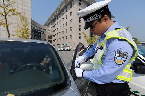 10月21日,杭州市高速交警第五大隊的一位交警為參加訓練營的車輛綁上藍絲帶。新華社記者 鞠煥宗 攝