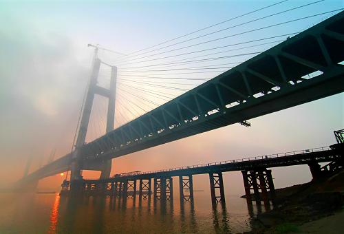 10月31日拍攝的湖北黃岡長(zhǎng)江大橋。當(dāng)日,目前世界同類橋梁跨度最大的湖北黃岡長(zhǎng)江大橋公路橋面板鋪設(shè)完成。湖北黃岡長(zhǎng)江大橋是長(zhǎng)江上第6座公路鐵路兩用橋,全長(zhǎng)4008米,設(shè)計(jì)為雙層橋面,下層為雙線高速鐵路,上層為四車(chē)道高速公路,主橋采用雙塔雙索面鋼桁梁斜拉橋方案,主跨567米,于2010年2月動(dòng)工,2012年9月實(shí)現(xiàn)大橋主跨鋼梁合龍,預(yù)計(jì)2013年底建成通車(chē)。建成后,將真正實(shí)現(xiàn)大別山革命老區(qū)湖北黃岡市與武漢從公路、鐵路及軌道交通方面全方位的“無(wú)縫對(duì)接”。新華社發(fā)