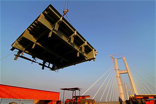 10月31日,工人在湖北黃岡長(zhǎng)江大橋上吊裝最后一塊公路橋面板。新華社發(fā)