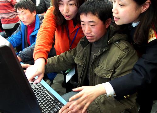 1月7日,來自重慶萬州的農(nóng)民工吳時明(右二)在工作人員的指導下購買春節(jié)回家的車票。當日,2013年春運首日車票開始發(fā)售,為此,上海鐵路局聯(lián)合上海東方信息苑推出幫助外來務工人員預訂“春運團體票”的服務。凡預訂團體火車票不便的零散外來務工者,只需自行組合湊滿6個人,即可在工作人員指導下預訂春運返鄉(xiāng)的車票。 新華社記者 陳飛 攝