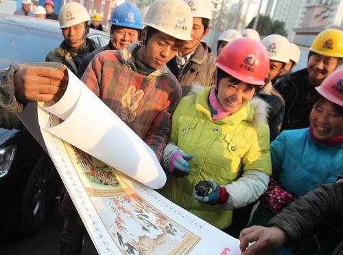 1月8日,外來(lái)務(wù)工人員在翻閱印有安全消防常識(shí)的掛歷。新華社記者 張明 攝
