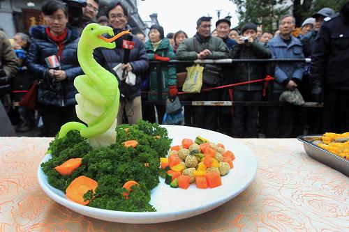 2月12日,“百家宴”上的一道名為《青蛇戲珠》的菜品吸引了眾多市民和游人的目光。當(dāng)日,杭州清河坊歷史街區(qū)舉辦“蛇年百家宴”,10余家餐飲商戶推出20多道各自拿手的特色菜肴,邀請市民、游客免費(fèi)品嘗,共同感受濃濃的親情和年味。新華社發(fā)(吳煌 攝)
