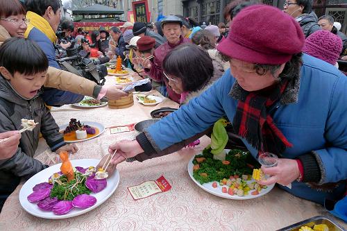 2月12日,市民和游客在品嘗“蛇年百家宴”上的特色菜肴。新華社發(fā)(施健學(xué) 攝)