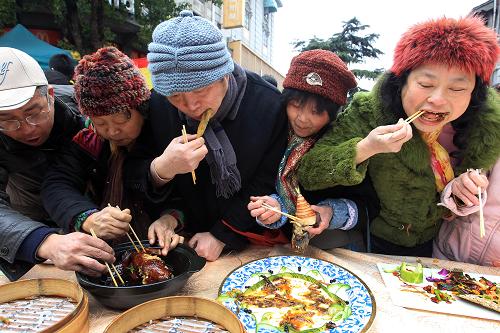 2月12日,市民和游客在品嘗“蛇年百家宴”上的特色菜肴。新華社發(fā)(吳煌 攝)
