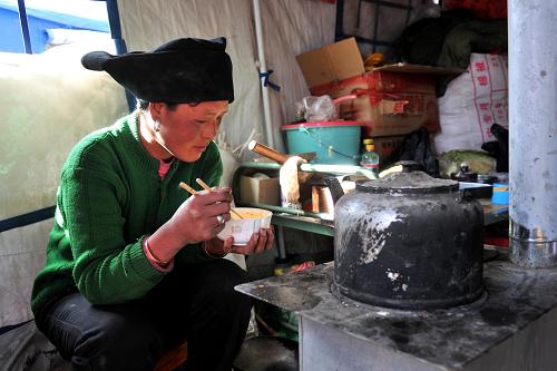 2月12日,受災(zāi)村民包秀英在黑多村的臨時安置點里吃飯。新華社記者 陳斌 攝