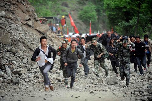 4月21日,前往寶興縣的解放軍救援官兵和群眾涉險(xiǎn)從滑坡現(xiàn)場穿過。當(dāng)日,受余震影響,通往災(zāi)區(qū)寶興縣城的210省道關(guān)言山段遭遇山體滑坡,救援人員正全力搶通。新華社發(fā)(薛玉斌 攝)