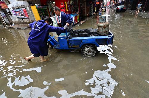5月15日,人們?cè)诜e水嚴(yán)重的江西省南昌市珠寶街棚戶區(qū)推車。新華社發(fā)(楊繼紅 攝)