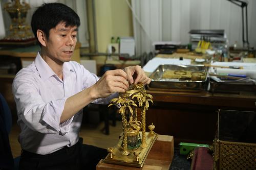 6月8日,故宮鐘表修復(fù)專家王津在工作室內(nèi)修復(fù)受損的清代銅鍍金轉(zhuǎn)花水法人打鐘。新華社發(fā)(劉長龍 攝)