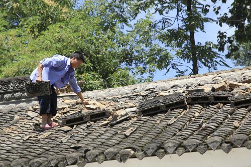 7月22日,甘肅省隴南市成縣城關(guān)鎮(zhèn)北山村村民在清理受損的房脊碎片。新華社發(fā)(吳庭棟 攝)