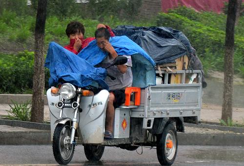 7月23日,在山東省蓬萊市,市民冒雨駕駛電動(dòng)車在道路上行進(jìn)。當(dāng)日,新一輪降雨開始影響山東,部分地區(qū)出現(xiàn)大暴雨。山東省國(guó)土資源廳和山東省氣象局聯(lián)合發(fā)布地質(zhì)災(zāi)害氣象風(fēng)險(xiǎn)黃色預(yù)警,提醒有關(guān)部門和人員做好防汛和山洪地質(zhì)災(zāi)害防御工作。新華社記者 朱崢 攝