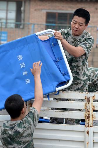 7月27日,救災(zāi)人員為宜川縣體育場搭建的臨時社區(qū)運送折疊床。新華社記者 李一博 攝