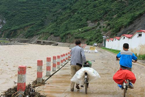7月27日,甘肅省隴南市成縣黃渚鎮(zhèn)幾名村民從暴雨沖過后的道路上經(jīng)過。新華社發(fā)(張平良 攝)