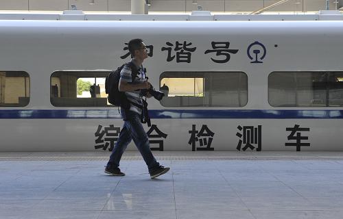 8月9日,一名攝影記者在向莆鐵路撫州站從聯(lián)調(diào)聯(lián)試綜合檢測(cè)車身旁走過。新華社記者 魯鵬 攝