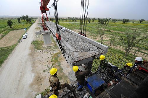 中鐵十一局三公司的鋪架人員在烏錫鐵路黃河特大橋上通過架橋機(jī)架設(shè)T型梁(8月19日攝)。新華社記者 郝同前 攝