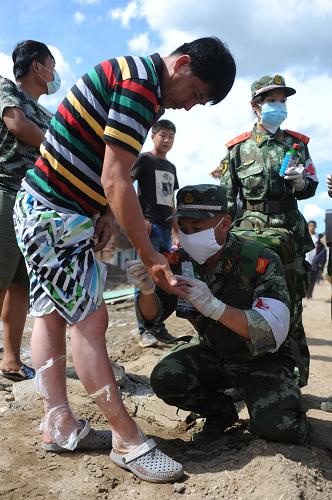 8月20日,武警醫(yī)護(hù)人員為村民處理傷口。新華社記者 潘昱龍 攝