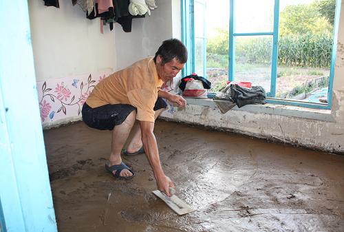 8月20日,撫松縣露水河鎮(zhèn)受災群眾重新抹平室內水泥地面。新華社記者 王猛 攝
