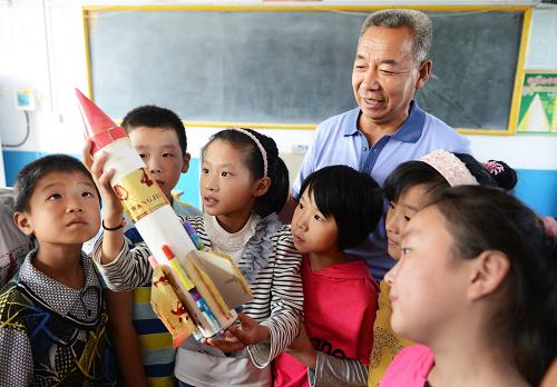 9月6日,張偉所帶四年級三班的學(xué)生張欣雅(左三)在給同學(xué)介紹自己制作的航天模型。新學(xué)期伊始,山東省鄒平縣南部山區(qū)臨池鎮(zhèn)南北寺小學(xué)的53歲教師張偉迎來了新班級的45名學(xué)生,他們中大多是附近山村的留守兒童。有著三十多年的農(nóng)村教學(xué)經(jīng)驗的張偉發(fā)現(xiàn),隨著鄉(xiāng)村外出打工者越來越多,班里的留守娃以及單親、失親學(xué)生也隨之增多,一些學(xué)生表現(xiàn)出孤僻、膽小、怯懦等性格,與以前的學(xué)生大有不同。為了孩子們能得到健全的身心發(fā)展,張偉除了關(guān)心孩子們的學(xué)習(xí)之外,還因材施教,針對留守兒童的需要關(guān)愛與溫暖的實際,每月走訪學(xué)生家庭了解情況,開展“班級是我家”、“我給爸媽說說話”等活動,讓學(xué)生們學(xué)會互相關(guān)愛,把班級當做自己的家,并幫助學(xué)生打電話和上網(wǎng)與在外地的家長溝通,用自己的努力和愛心守護著當?shù)氐牧羰貎和?。新華社發(fā)(董乃德 攝)