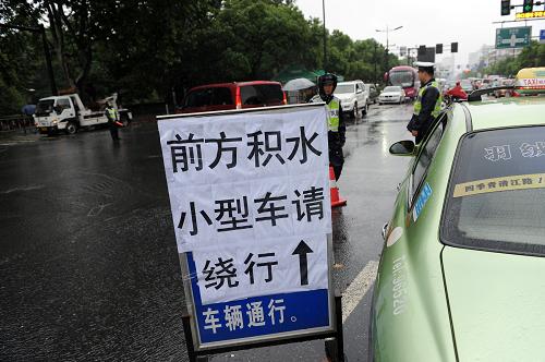 10月8日,在杭州市北山路和環(huán)城西路路口,交警在提示牌前提醒小型車輛繞行避開積水路段。新華社記者 鞠煥宗 攝