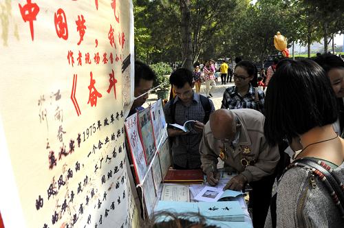 10月13日,在濟南泉城廣場,購書的年輕人讓王洪利老人在他的《奮斗》一書上留言。新華社記者 馮杰 攝