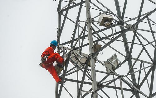 10月17日,國網(wǎng)湖州供電公司工作人員正在長興縣夾浦鎮(zhèn)110千伏輸電線路鐵塔安裝在線視頻監(jiān)測裝置,包括攝像頭、太陽能板、電池以及傳輸設(shè)備。新華社記者 徐昱 攝