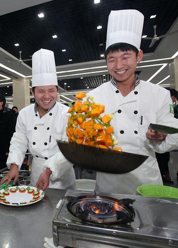 12月2日,美食周活動(dòng)中,兩名大學(xué)生在烹飪美食。新華社發(fā)(劉東岳 攝)