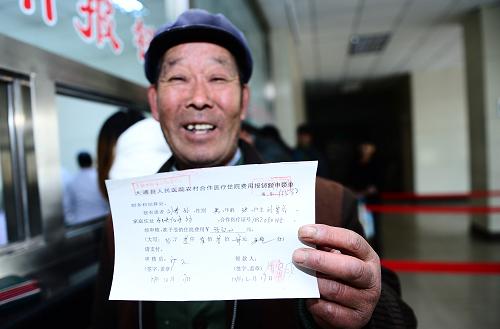 12月18日,在青海省大通回族土族自治縣人民醫(yī)院,63歲的劉富成在展示兒子住院費(fèi)用的報(bào)銷單。新華社記者 張宏祥 攝