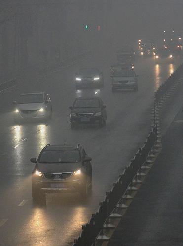 1月31日,在鄭州市區(qū)的道路上,車輛在霧中行駛。 新華社記者 王頌 攝