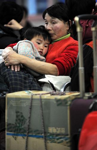 1月22日,在南昌火車站候車室,一名孩子躺在親人的懷抱中候車。新華社記者 周科 攝