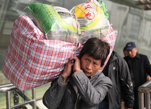 2月6日,一名外來務(wù)工者扛著行李走出南京火車站。新華社發(fā)(李文寶 攝)