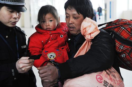 2月19日,在合肥火車站,一名懷抱小孩的旅客向車站民警咨詢乘車情況。新華社記者 李健 攝