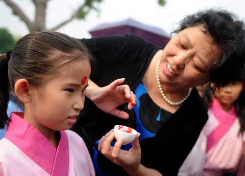 6月6日,一名老師給參加祭祀活動(dòng)的小朋友點(diǎn)朱砂痣。新華社記者 羅曉光 攝