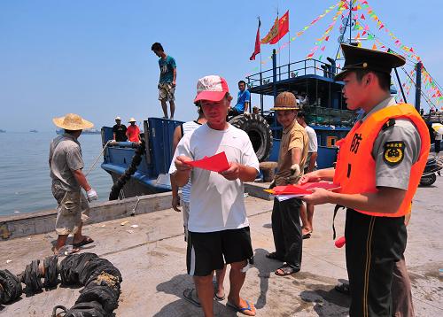 8月1日,在中國(guó)四大漁港之一的福建省石獅市祥芝漁港碼頭,福建石獅邊防大隊(duì)官兵把宣傳材料送到出海漁民手中。新華社記者 魏培全 攝