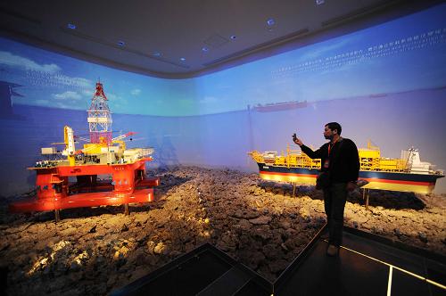2010年5月9日,一位游客在上海世博會(huì)中國(guó)船舶館展示的鉆井平臺(tái)和半潛式儲(chǔ)油船模型的能源區(qū)拍照。新華社記者郭昱攝
