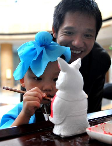 9月11日,一名小朋友在家長(zhǎng)的指導(dǎo)下給兔爺模型涂色。新華社記者 劉瀟 攝