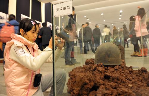 12月3日,一名小女孩在展廳內(nèi)拍攝二戰(zhàn)時(shí)期美軍在中緬印戰(zhàn)場(chǎng)使用的鋼盔。新華社記者 劉潺攝