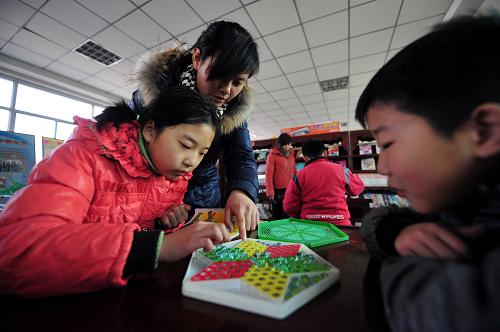 2月16日,在工農(nóng)路街道的“留守兒童之家”,輔導(dǎo)老師在指導(dǎo)小朋友下跳棋。新華社記者張錳攝