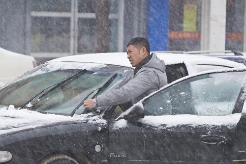 12月3日,在吉林省吉林市街頭,一名男子在雪中調(diào)整車輛的雨刷器。新華社發(fā)(孫鑫 攝)