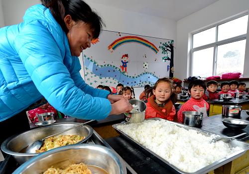 12月19日,青龍滿族自治縣七道河鄉(xiāng)后水河小學(xué)的老師在給孩子們盛飯。新華社記者 楊世堯 攝