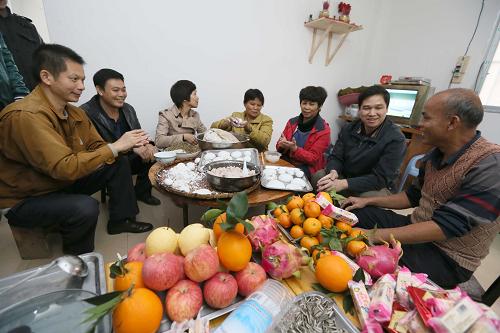 12月21日,在南寧市西鄉(xiāng)塘區(qū)新陽街道辦永和村臨時安置房里,3戶水上人家安置戶和街道工作人員一起包湯圓,過冬至。新華社記者 周華 攝