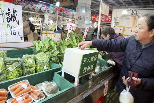12月29日,居民在上海普陀區(qū)藍(lán)田菜場(chǎng)無(wú)人銷售蔬菜試銷點(diǎn)挑選好蔬菜后投幣付款。新華社發(fā)(莊毅 攝)