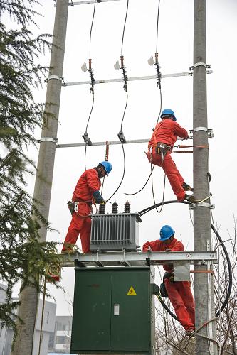 1月22日,浙江長興縣供電局工作人員在南莊村架設配電變壓器。新華社記者 徐昱 攝