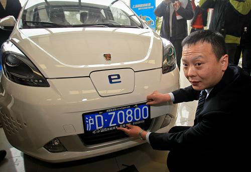 1月23日上午,上海首位獲得新能源汽車免費牌照的錢先生和愛車合影。新華社發(fā)
