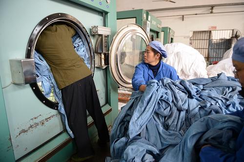 1月25日,在南昌鐵路局客技站洗衣廠,工作人員在將列車上的臥具塞進(jìn)洗衣機(jī)清洗。新華社記者 周密 攝