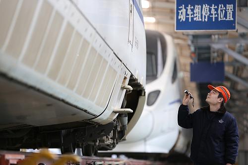 1月25日,鄭州鐵路局車輛段的工人在對準(zhǔn)備出庫的動車組進(jìn)行最后檢查。新華社發(fā)(祝慶 攝)
